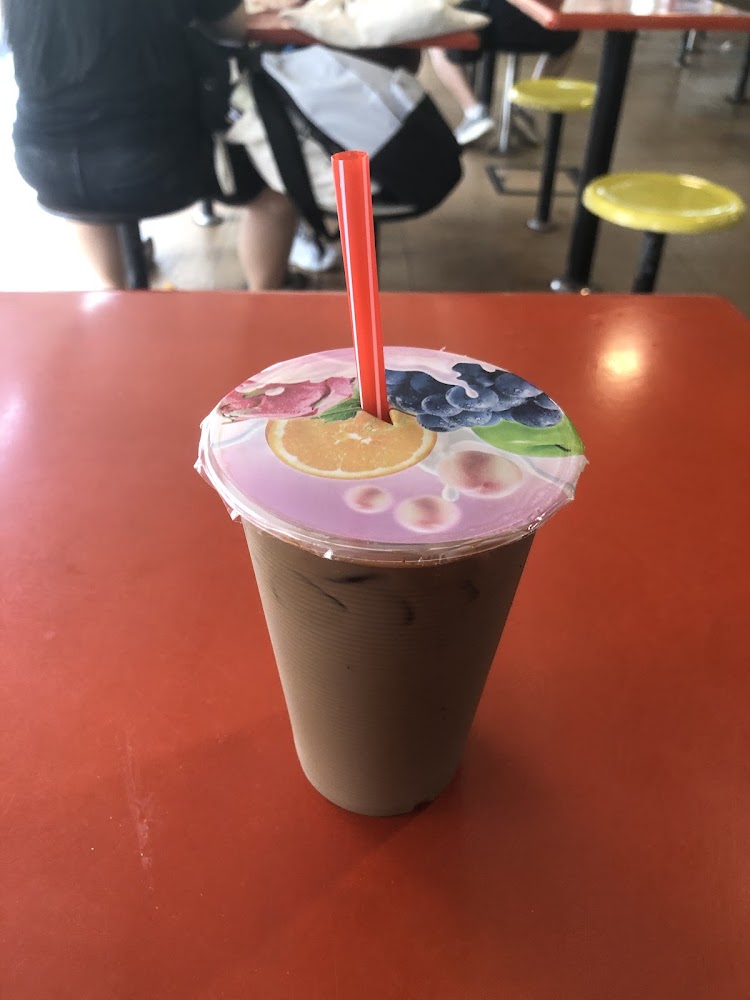 Iced kopi in a plastic cup on the red kopitiam table